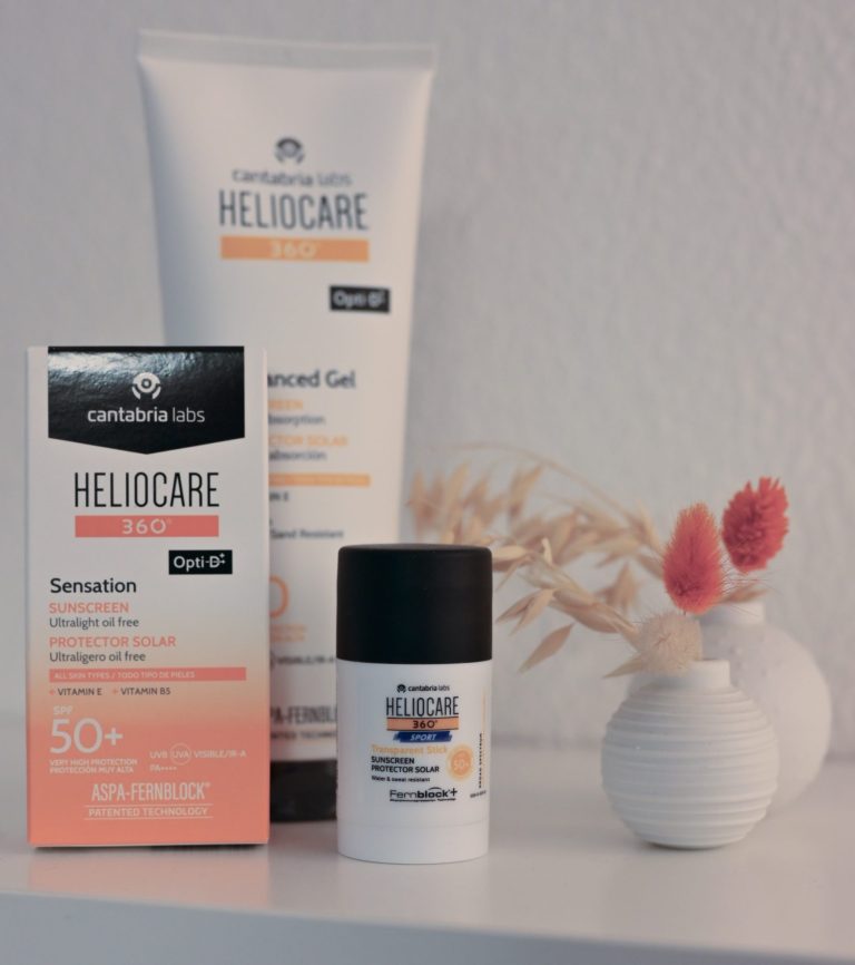 Zorgproducten van Heliocare met zonnebrandcrème en een doosje, naast decoratieve vazen.